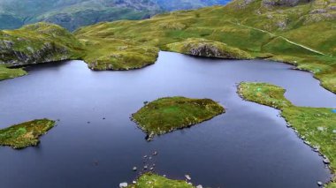 Yazın bulutlu gökyüzü ve arka planında dağlar ve vadiyle Tarn Gölü 'nün tepesinden geçen hava aracı görüntüleri.