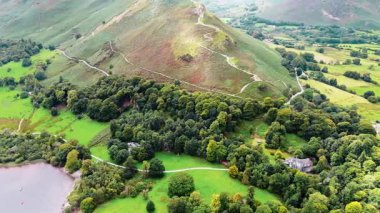 Hava aracının sağ kanadı, dağların alçak açısını ve İngiltere Gölü 'ne giden yolu gösteriyor. Ulu su gölü manzaralı, doğa manzaralı ve yazın etrafı bulutlu gökyüzü ile çevrili vadilerle çevrili.