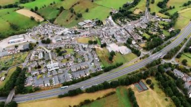Eski İngiliz köyünün insansız hava aracı görüntüsü üzerinde yüksek açı var. Yazın kırsal alanda, çift yönlü geçitin yanında tarlalar var.