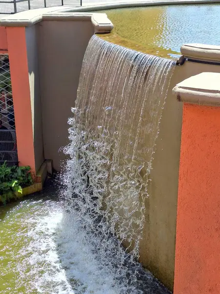 Duvardan aşağı akan güzel bir şelalenin güneş ışığını yansıtan yumuşak turuncu bir tonu vardır. Su damlacıkları, huzurlu ve rahatlatıcı bir ortamda büyüleyici bir görsel manzara yaratırlar..