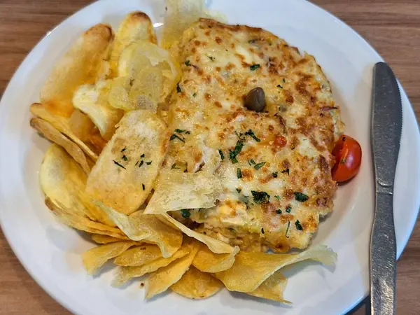 Fırında eritilmiş peynirin bir kısmını çevreleyen çıtır patates cipsleri üzerine doğranmış domates ve taze otlar konan lezzetli bir yemek. Atıştırmalık veya aperatif için mükemmel..