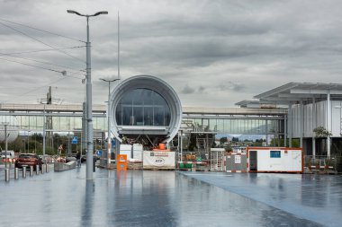 Ziyaretçiler, CERN 'in modern dairesel binalarının önünden bulutlu gökyüzünün altında yürüyorlar.. 