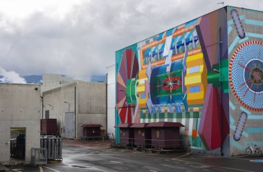 Parçacık hızlandırıcıyı tasvir eden renkli duvar resmi bulutlu gökyüzünün altında bir CERN binasını süslüyor. Büyük Hadron Çarpıştırıcısı 'nın bölgesi. 20 Haziran 2023. Yüksek kalite fotoğraf