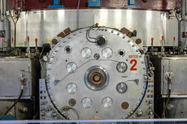 Bilimsel bir araştırma tesisi içinde ROTCO 2 etiketli, detaylı mühendislik ve endüstriyel tasarımı gösteren büyük dairesel bir metalik bileşenin ön görüntüsü. Yüksek kalite fotoğraf