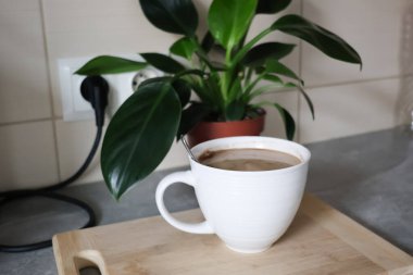 Sıcak bir sabah mutfakta, beyaz seramik bardakta bir fincan sıcak kahveyle.