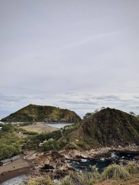 Kayalık tepeleri ve küçük bir plajı olan kıyı manzarası. Payangan Plajı Jemonu