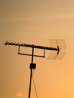 Classic Outdoor TV Antenna Silhouette at a Golden Sunrise clipart