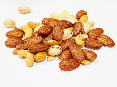 Temiz beyaz bir zemin üzerinde canlı bir badem, kaju ve şam fıstığı karışımı sağlıklı yemek ve organik beslenme kavramları için mükemmel..