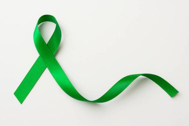 Zihinsel sağlık desteğini, organ bağışını ve temiz beyaz arka planda çevresel nedenleri sembolize eden yeşil farkındalık kurdelesi.