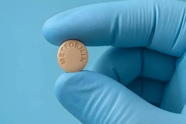 Sağlık hizmetlerinde diyabet tedavisinde kullanılan metformin tableti tutan eldivenli parmaklara yakın çekim