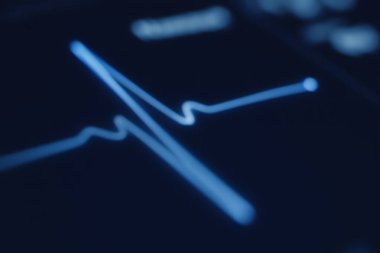 Koyu ekran üzerinde parlayan mavi EKG dalga formu, kalp izleme, kardiyak tanı ve gelecekteki tıbbi teknolojiyi sembolize ediyor..