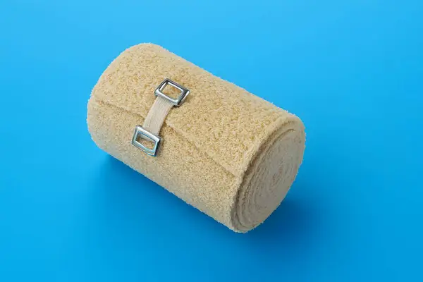 Mavi yüzeyinde çift tokalı kayışla sarılmış bej havlu ya da battaniye, hijyen, konfor ve organize tıbbi ya da sağlık malzemelerini simgeliyor.