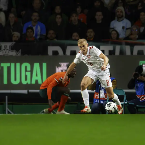 Lizbon, Portekiz. 23 Mart 2025. UEFA Uluslar Ligi: Portekiz - Danimarka. Denmar takımından Gustav Isaksen (8) Nuno Mendes 'in yanından geçti