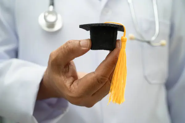 Hastanede mezun şapkası tutan Asyalı kadın doktor. Tıp eğitimi almış..