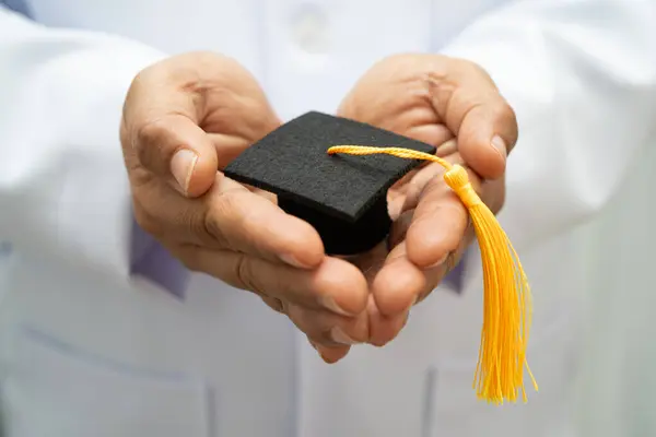 Hastanede mezun şapkası tutan Asyalı kadın doktor. Tıp eğitimi almış..