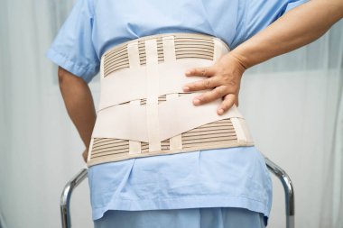 Asya baş ağrısı. Esnek destek kemeri takıp yürüteç takıyor..