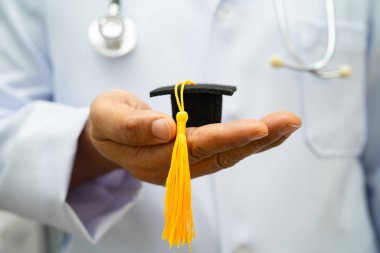 Hastanede mezun şapkası tutan Asyalı kadın doktor. Tıp eğitimi almış..