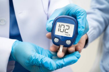 Diyabet tedavisinde kan şekeri seviyesini kontrol etmek için dijital glikoz ölçer kullanan Asyalı doktor.