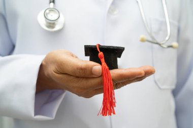 Hastanede mezun şapkası tutan Asyalı kadın doktor. Tıp eğitimi almış..