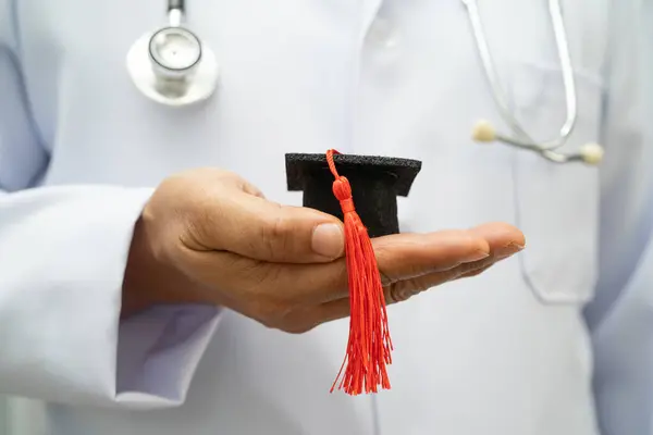 Hastanede mezun şapkası tutan Asyalı kadın doktor. Tıp eğitimi almış..