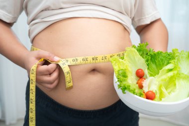 Koca göbekli, şişman, kilolu ve sağlıklı yiyecekleri olan Asyalı bir kadın..