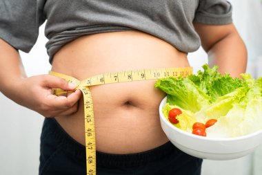 Koca göbekli, şişman, kilolu ve sağlıklı yiyecekleri olan Asyalı bir kadın..