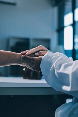 Yakın plan, doktor yaşlı bir kadınla el ele tutuşuyor ve kanser bakımı ya da destek. Sağlık hizmetleri veya güven, empati veya şefkat ve kadın bakıcı veya hemşire umut ve şefkat için yaşlı kişinin elini tutuyor.