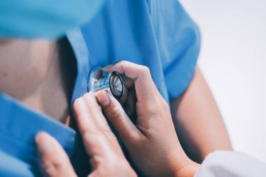 Ev bakımı hemşiresi ve yaşlılar kardiyoloji sağlık hizmetleri. Genç İspanyol kadın doktor hemşirenin yakın çekimleri sırasında steteskop kullanarak olgun beyaz hasta kalp atışlarını kontrol et.