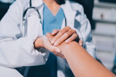 Yakın plan, doktor yaşlı bir kadınla el ele tutuşuyor ve kanser bakımı ya da destek. Sağlık hizmetleri veya güven, empati veya şefkat ve kadın bakıcı veya hemşire umut ve şefkat için yaşlı kişinin elini tutuyor.