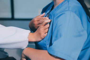 Ev bakımı hemşiresi ve yaşlılar kardiyoloji sağlık hizmetleri. Genç İspanyol kadın doktor hemşirenin yakın çekimleri sırasında steteskop kullanarak olgun beyaz hasta kalp atışlarını kontrol et.