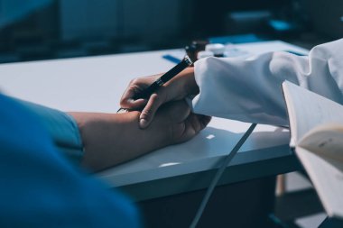 Steteskopla sfenometre kullanan bir doktor hastanede kan basıncını ölçüyor..