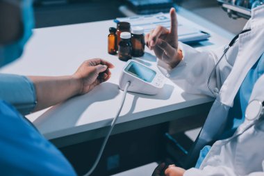 Steteskopla sfenometre kullanan bir doktor hastanede kan basıncını ölçüyor..