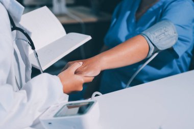 Steteskopla sfenometre kullanan bir doktor hastanede kan basıncını ölçüyor..