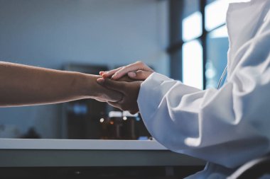 Yakın plan, doktor yaşlı bir kadınla el ele tutuşuyor ve kanser bakımı ya da destek. Sağlık hizmetleri veya güven, empati veya şefkat ve kadın bakıcı veya hemşire umut ve şefkat için yaşlı kişinin elini tutuyor.