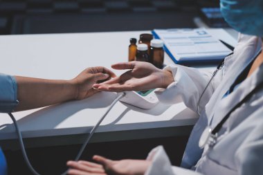 Steteskopla sfenometre kullanan bir doktor hastanede kan basıncını ölçüyor..