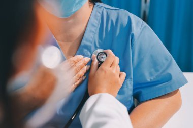 Ev bakımı hemşiresi ve yaşlılar kardiyoloji sağlık hizmetleri. Genç İspanyol kadın doktor hemşirenin yakın çekimleri sırasında steteskop kullanarak olgun beyaz hasta kalp atışlarını kontrol et.