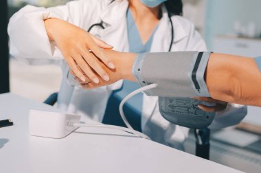 Steteskopla sfenometre kullanan bir doktor hastanede kan basıncını ölçüyor..