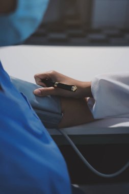 Steteskopla sfenometre kullanan bir doktor hastanede kan basıncını ölçüyor..