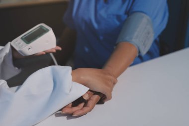 Steteskopla sfenometre kullanan bir doktor hastanede kan basıncını ölçüyor..