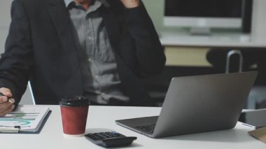 Ofiste hesap makinesi ve dizüstü bilgisayar kullanan iş adamı