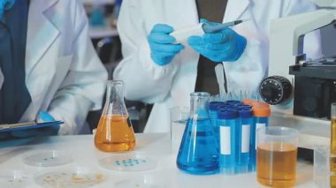 Laboratuvarda kimyasal test tüpleri ve ekipmanlarıyla çalışan bilim adamları