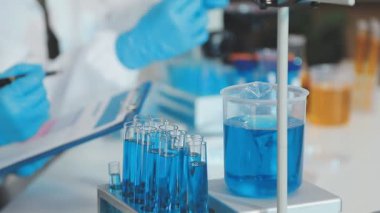 Laboratuvarda mavi sıvıyla laboratuvar asistanı. kimya laboratuvarı.