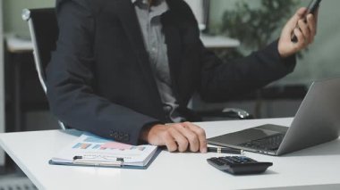 Çalışma masasında bilgisayar ve hesap makinesiyle çalışan iş adamı