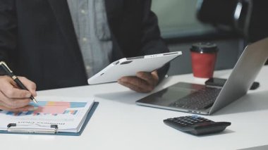 Modern ofisteki masada dizüstü bilgisayar ve hesap makinesi kullanan iş adamı.