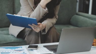 Genç iş kadını ofisteki not defterine dizüstü bilgisayar ve yazı kullanıyor.