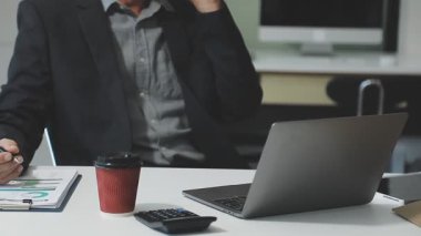 İşadamı ofiste dizüstü bilgisayar ve akıllı telefonla çalışıyor.