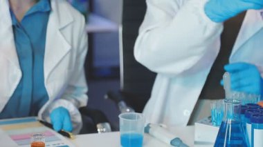 Laboratuvarda elinde sıvı şişeyle üniformalı iki bilim adamının yakın çekimi. Bilimsel ve bilimsel kavram.