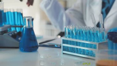 Laboratuvar asistanı bardağı kimyasal sıvıyla tutuyor.