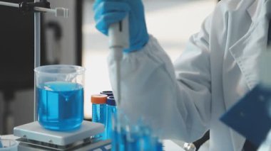 Koruyucu kıyafetli kadın araştırmacı laboratuvarda mikroskopla laboratuvar deneyi üzerinde çalışıyor..