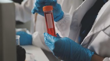 Laboratuvardaki bilim adamı sıvı tüp tutuyor.